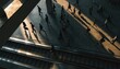 © thanawat - People walking across a sunlit urban area casting long shadows, viewed from above, near escalators or stairs in a modern architectural setting.