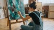 © utaem2022 - Artist painting abstract teal artwork on canvas using brush in rustic studio