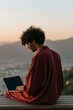 © Andrii Zastrozhnov - Young man using laptop at a hillside overlook during sunset for website banner and remote work background imagery