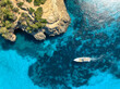 © den-belitsky - Aerial view of luxury motor boat yacht in turquoise sea water in Mallorca, Balearic island, Spain. Speedboat moving near rocky cliff coast. Drone summer landscape. Cruise. Top down view. Travel