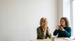 © Tri - Two women communicating through sign language in a bright room