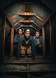 © Ryzhkov - Mixed inspection team and homeowner crawling through a dark attic under wooden rafters for home maintenance services, property evaluation and damage discovery