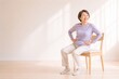 © Eldergrace - Senior Japanese woman doing pelvic exercise while seated for frailty prevention, wide shot