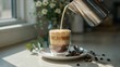 © Design_Gallary - Coffee being poured into a clear glass cup on a white saucer with coffee beans