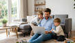 © DIGADO - Smiling Parents with Son and Daughter Enjoying Quality Time Together Using Laptop on Comfortable Sofa in Modern Living Room at Home