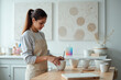 © YouraPechkin - Woman Stirring Beverage in Mug on Wooden Table in Bright Studio