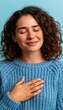 © spyrakot - Woman with hand on chest expressing calm and gratitude on pale blue background