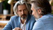 © Mrammon - Mature mentor business coach senior man gray hair beard serious expression conversation guidance office support Mature mentor and business coach with gray hair and beard serious conversation