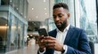 © Eve - Focused African American businessman using smartphone in modern corporate office building texting client reading financial news browsing business application executive messaging online