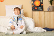 © Pixel-Shot - Happy young boy in astronaut costume sitting on floor, childhood dreams of space exploration and future career aspirations