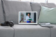 © Pixel-Shot - Screen of laptop with teacher giving online lesson on sofa in room