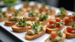 © Nataliia_Trushchenko - Assorted canapes with fresh toppings including cherry tomatoes and herbs arranged on a white platter, ideal for catering or gourmet events