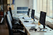 © DragonImages - Wide shot of empty call center workstations displaying customer support software in team office, representing service operations and staffing needs. For contact center marketing