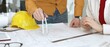 © rogerphoto - Construction professionals analyzing architectural plans and schematics, developing a building project onsite, ensuring efficiency and precision in design and engineering
