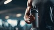 © Thailand Smile - Muscular fitness athlete holding a red protein shaker bottle. Fit man and bodybuilder with sports nutrition supplement container.