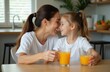 © Vadym - Mother and daughter share juice at kitchen table. Woman touches girl nose, both smile. Family bonding over drink at home. Healthy lifestyle moment.