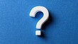 © Akash - White question mark symbol on a textured blue fabric background