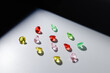© Parilov - Assorted colorful gemstones diamonds displayed on smooth white surface under dramatic lighting