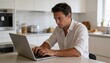 © Future Vision - Typing man in white shirt, rolled sleeves, working on laptop at kitchen island, with toaster