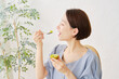 © siro46 - リビングでキウイフルーツを食べる女性