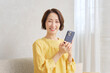 © siro46 - リビングでスマートフォンを使う女性　ポートレート　カメラ目線