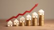 © Prapan - Real Estate Market Growth: Miniature houses are stacked on coins, arranged in increasing height and value, symbolizing the upward trend of property prices, with a red arrow graph indicating growth.