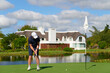 © khmelev - Man putting golf ball on green near water.