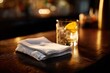 © Anatolii Rymarchuk - Elegant bar scene: single napkin on a glossy counter, warm lighting, and a background drink