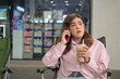 © Ranta Images - Transgender Thai Isan woman talking on her smartphone while holding an iced coffee outdoors