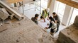 © Mr. Bolota - Um grupo de trabalhadores da construção civil analisa plantas em um canteiro de obras.