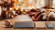 © peacefy - Cozy autumn scene on a wooden desk featuring a steaming cup of tea, a closed laptop, a notebook, and a modern trackpad, with a blurred background of fall foliage and bokeh lights.