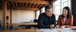 © Fernando - Asian business partners reviewing contract paper at desk in modern office, mature mentor advising agency manager, financial planning and teamwork meeting, collaborative professional consulting office.