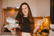 © zvkate - Disgusted and annoyed young woman looking away with look of disapproval, holding clear plastic containers for recycling in messy kitchen, feeling repulsed by packaging waste and domestic clutter.