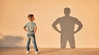 © Rayn - A little boy standing with hands on hips looking at his shadow cast as a strong muscular adult man on the wall, symbolizing future potential, growing up, ambition, and confidence.