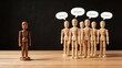 © Penelope - Sad wooden doll isolated from group, bullying and social exclusion concept, lonely figure facing crowd with speech bubbles, depression, discrimination, minority rejection