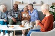© Prostock-studio - Joyful Senior Group Of Five Diverse Friends Having Fun Together Over Coffee And Cookies At Home, Smiling And Engaged In Conversation, Cozy Living Room Setting For Social Interaction.