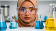 © VIRTA JUHO MIKKO - Muslim female scientist wearing hijab and safety goggles in a laboratory. Researcher stands behind beakers with colorful solutions. STEM diversity concept for healthcare and biotechnology marketing.