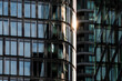 © yaqui_villegas - Between curved glass tower facades, sunlight sharpens modern skyscraper architecture as reflections, windows and office exterior overlap