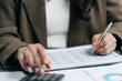 © winnievinzence - Accountant using pen and calculator to review a financial data report on office desk, businesswoman auditing business tax, budget or investment profit