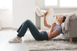 © Pixel-Shot - Young pretty woman with hand fan suffering from heat and lying on floor in living room