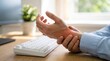 © RAAL - Office worker holding painful wrist at desk with keyboard, suffering from carpal tunnel syndrome
