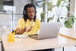 © anatoliycherkas - African american man having a virtual meeting on a laptop, working remotely with headphones in a modern office