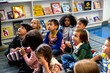 © Rawpixel.com - Diverse group of children sitting on the floor in a library setting.