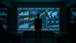 © Ro - Man looking at large screen with graphs and charts in a dark room.