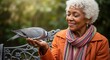 © RitaRuhi - Senior african american woman feeding a pigeon in a park setting