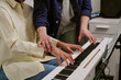 © AnnaStills - Teenager practicing piano with instructor guiding hand position on keyboard, showing music education and skill development. Useful for learning programs, tutoring services, close up shot