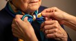 © FashionFarmer - Close-up of caregiver hands tying a blue and yellow silk scarf around an elderly woman's neck