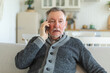 © Юлия Завалишина - Happy middle aged senior man talking on smartphone with family friends. Older mature grandfather with cell phone talking with grown up children, resting at home. Older generation modern tech usage