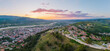 © AmazingAerialAgency - Aerial view of the historic Berat Castle walls and the Osum River valley at sunset with red-tiled rooftops and rolling green hills in Berat, Berat County, Albania.
