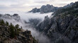 © Sekai - Deep mountain ravine is enveloped in thick morning fog showing jagged granite cliffs landscape view.